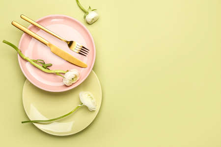 Simple table setting and ranunculus flowers on color background