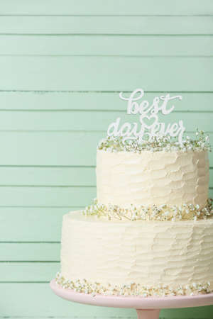 Dessert stand with beautiful wedding cake and text BEST DAY EVER on color wooden background