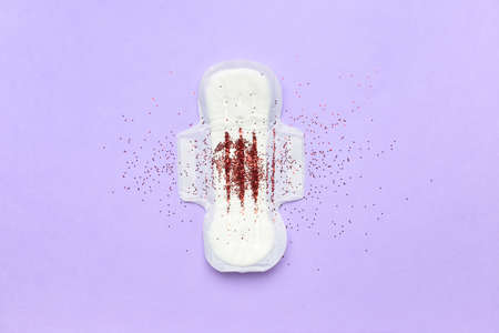 Confetti and menstrual pad on purple background