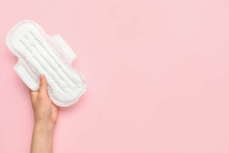 Female hand with menstrual pad on pink backgroundの写真素材