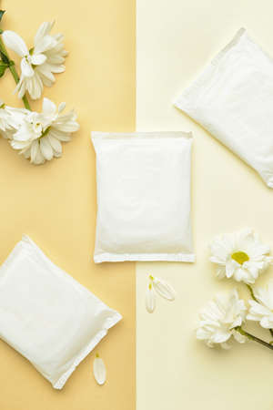 Menstrual pads and flowers on yellow background