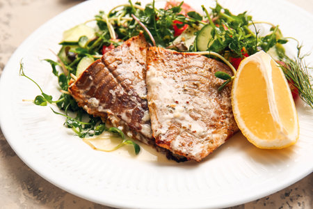 Plate with tasty baked cod fillet and vegetables on light background, closeupの写真素材
