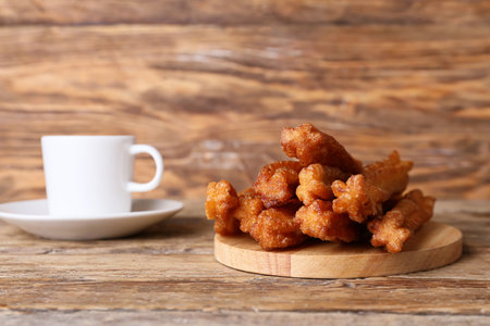 Board with tasty churros and cup of hot coffee on wooden backgroundの写真素材