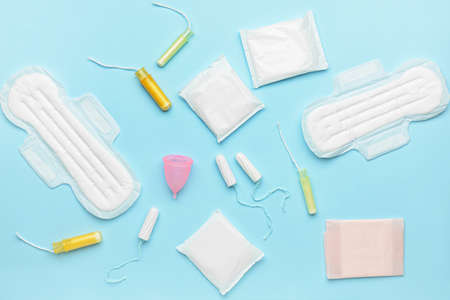 Menstrual cup, pads and tampons on blue background