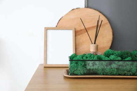 Container with decorative moss on table in bedroom, closeup
