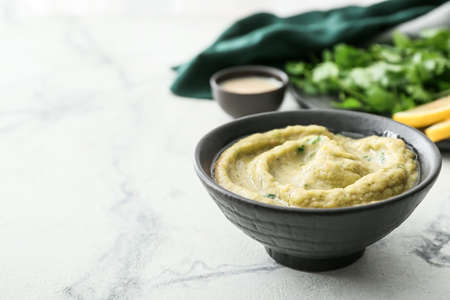 Bowl with tasty baba ghanoush on light background, closeup