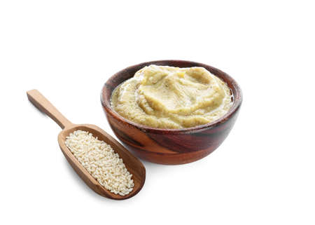 Bowl with tasty baba ghanoush and scoop of sesame on white background