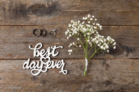 Wedding and engagement rings, gypsophila flowers, text BEST DAY EVER on wooden backgroundの写真素材