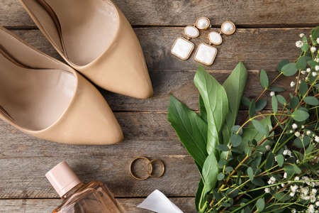 Wedding rings, stylish bride accessories and bouquet of flowers on wooden background, closeupの写真素材