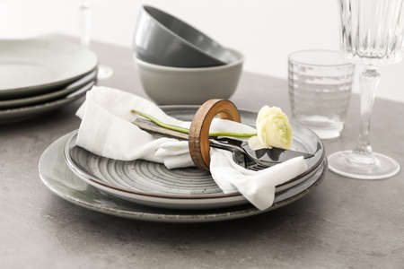 Stylish table setting and ranunculus flower on gray background