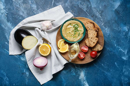 Bowl with tasty baba ghanoush and ingredients on color backgroundの写真素材