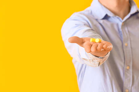 Young man with ear plugs on yellow background, closeupの写真素材