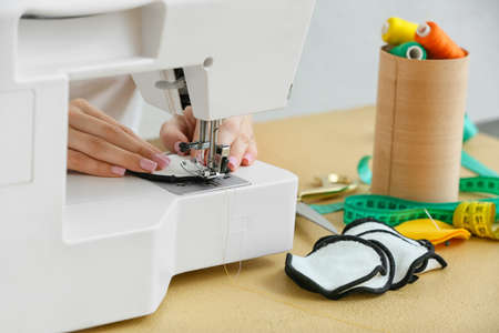Woman sewing reusable cotton pad at table, closeup