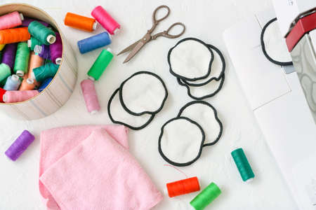 Handmade cotton pads with threads, scissors and fabric on white background