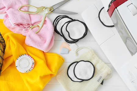 Handmade cotton pads with materials on white wooden background
