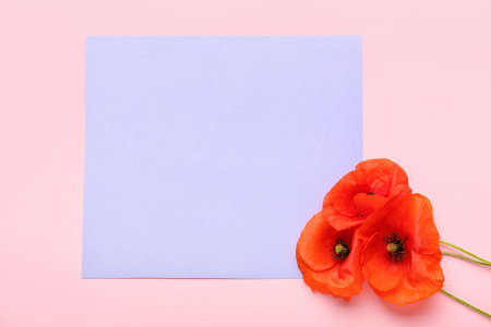 Beautiful red poppy flowers and paper sheet on color backgroundの写真素材