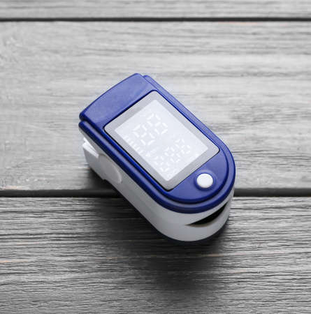 Pulse oximeter on dark wooden background, closeup