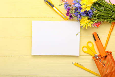 Blank sheet of paper, bouquet of flowers and stationery on color wooden background, closeup