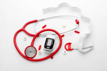 Composition with pulse oximeter and stethoscope on white background