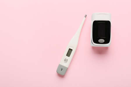 Pulse oximeter and thermometer on color background