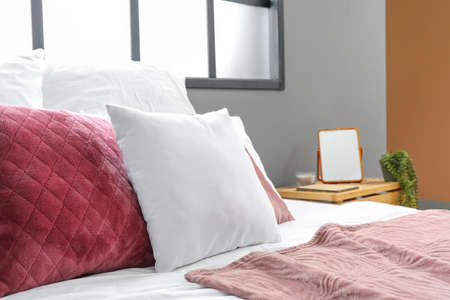 Comfortable bed with pink and white pillows in modern room