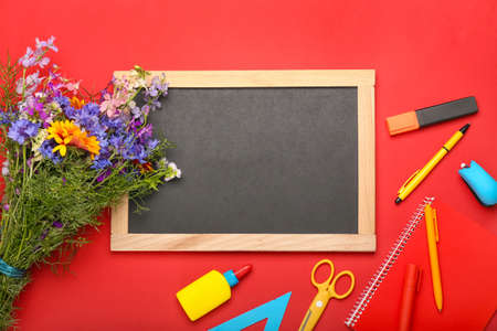 Blank chalkboard, bouquet of beautiful wild flowers and stationery on color backgroundの写真素材