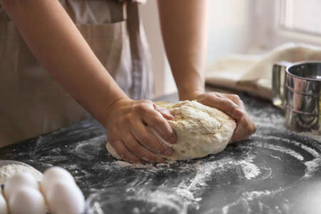 Female chef preparing dough on kitchen table, closeupの写真素材