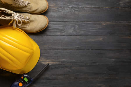 Safety hardhat with shoes and radio transmitter on dark wooden backgroundの写真素材