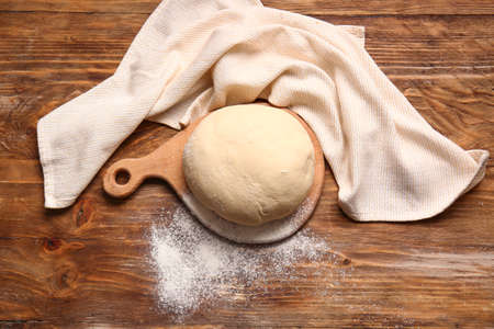 Board with fresh dough on wooden backgroundの写真素材