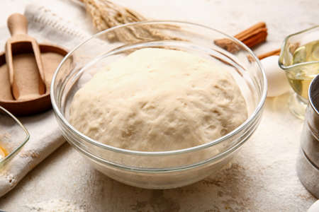 Bowl with fresh dough on light backgroundの写真素材