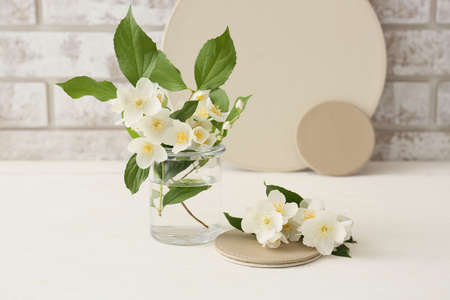 Composition with beautiful jasmine flowers on table against brick wall