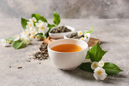 Composition with cup of jasmine tea, dry leaves and flowers on grunge backgroundの写真素材