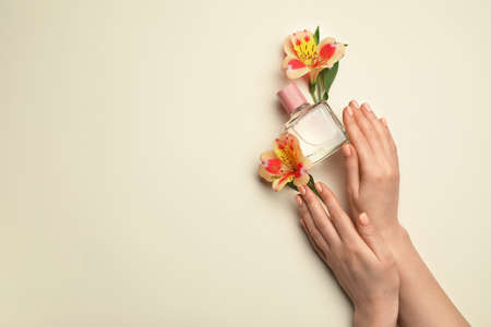 Hands with beautiful manicure, flowers and perfume on light backgroundの写真素材