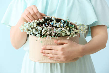 Woman with beautiful manicure, flowers and cosmetic bag on color background, closeup