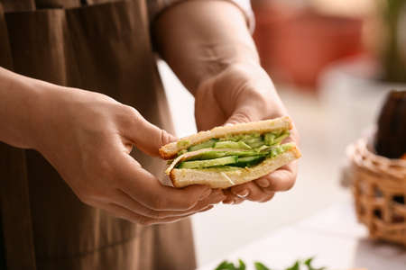 Woman holding tasty sandwich in kitchen, closeupの写真素材