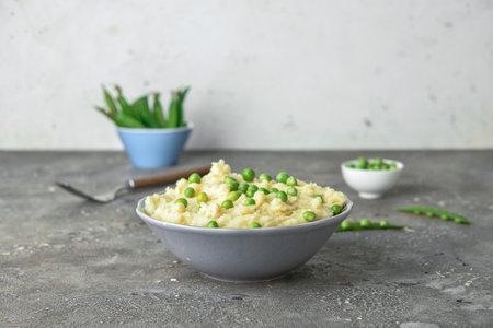 Bowl with mashed potatoes and green peas on tableの写真素材