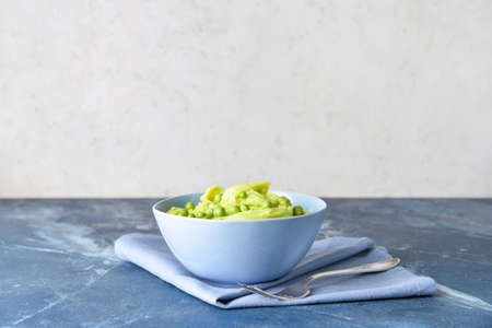 Bowl with mashed potatoes and green peas on table