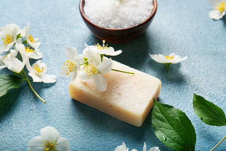 Soap bar, sea salt and jasmine flowers on color backgroundの写真素材