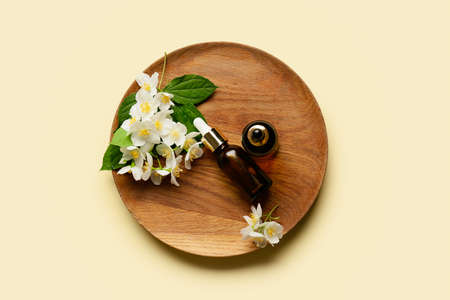 Plate with bottles of essential oil and jasmine flowers on color backgroundの写真素材