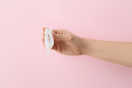 Female hand with menstrual cup on pink backgroundの写真素材