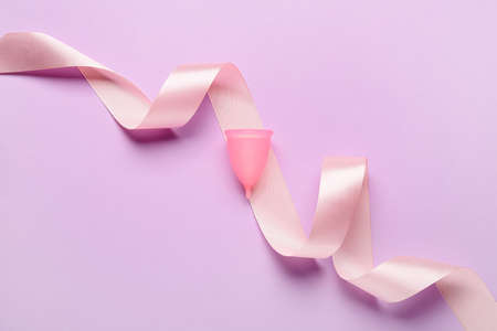 Menstrual cup and ribbon on color backgroundの写真素材