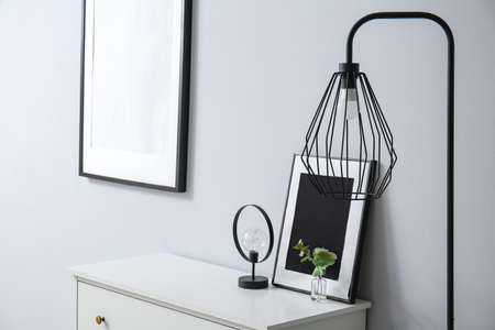 Frame, eucalyptus branches and lamp on shelf near light wallの写真素材