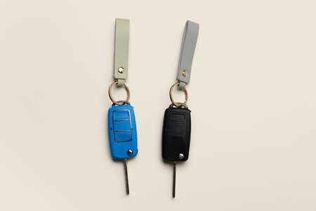 Car keys with leather keychains on light background