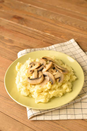 Plate with tasty mashed potatoes and mushrooms on wooden backgroundの写真素材
