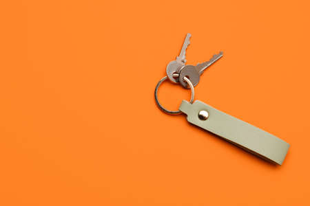 Keys with leather keychain on color background
