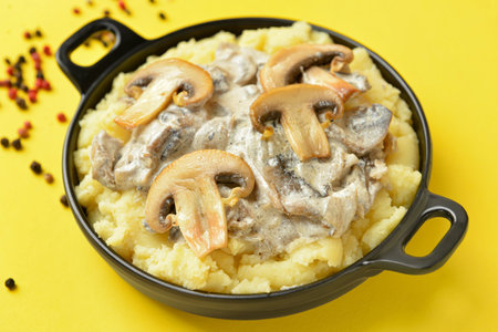 Frying pan with tasty mashed potatoes and mushrooms on color backgroundの写真素材