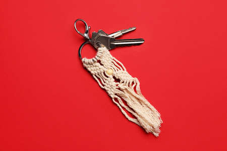 Keys with handmade cotton keychain on color background