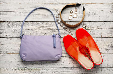 Trendy handbag, shoes and different accessories on wooden background