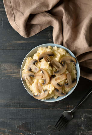 Bowl with tasty mashed potatoes and mushrooms on dark wooden backgroundの写真素材