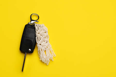 Car key with handmade cotton keychain on color background